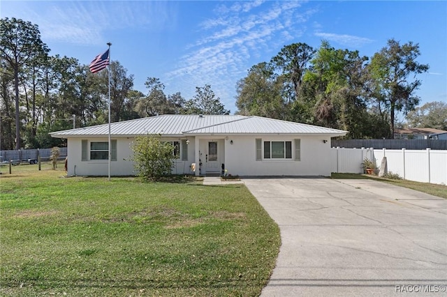 ranch-style house featuring metal roof, a front lawn, fence, and stucco siding