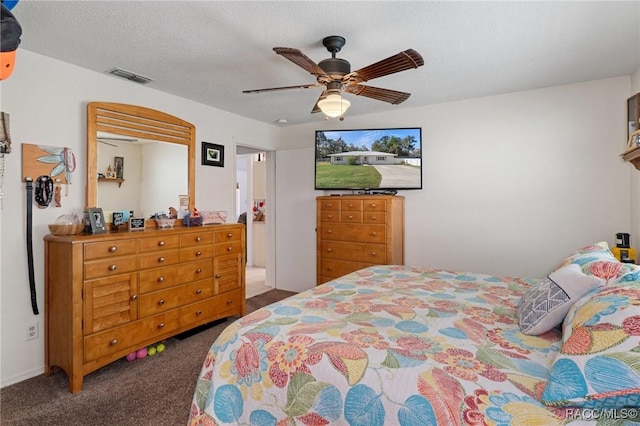 bedroom featuring visible vents, dark carpet, a textured ceiling, and ceiling fan