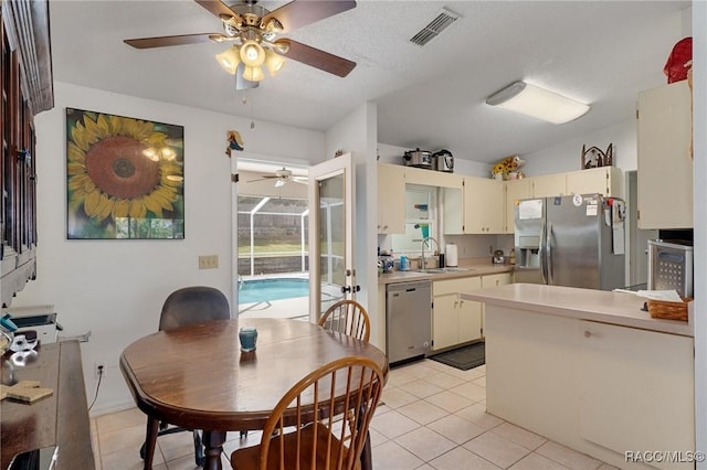 kitchen featuring cream cabinets, stainless steel appliances, a sink, visible vents, and light countertops