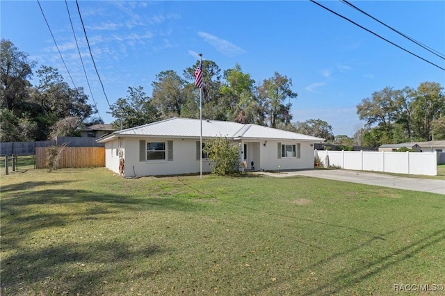 view of front facade featuring metal roof, concrete driveway, a front yard, and fence