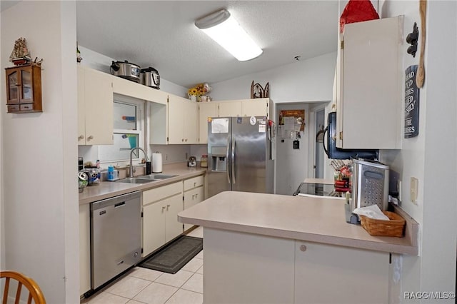 kitchen with light countertops, appliances with stainless steel finishes, a peninsula, and a sink