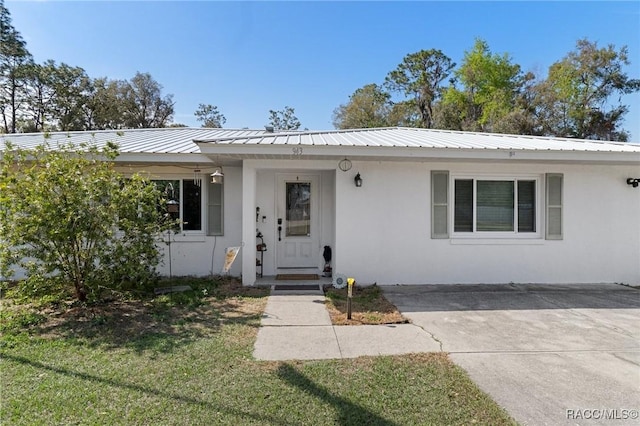 view of front of home featuring stucco siding, metal roof, and a front yard