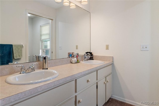 bathroom featuring double vanity, a sink, and baseboards