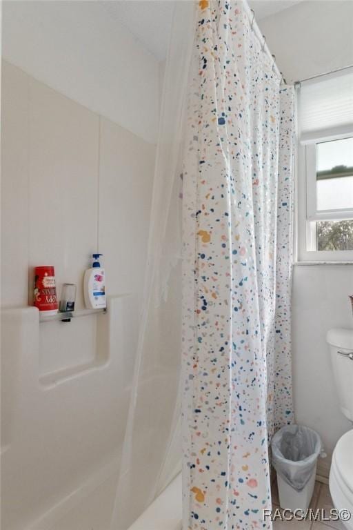 full bath with a shower with shower curtain and toilet