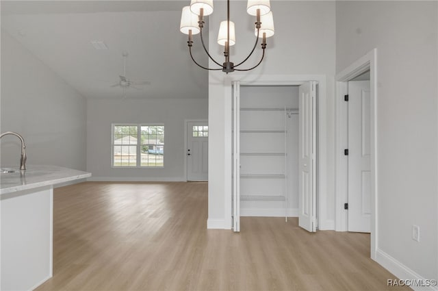 unfurnished dining area featuring ceiling fan with notable chandelier, light hardwood / wood-style flooring, and sink