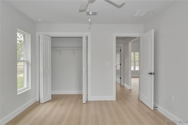 unfurnished bedroom featuring ceiling fan, light hardwood / wood-style floors, a closet, and multiple windows