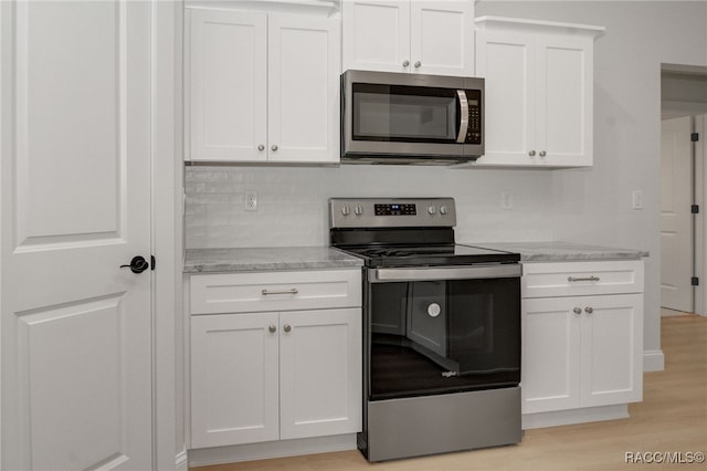 6526 N Earlshire Ter, Citrus Springs, FL 34434 - kitchen featuring appliances with stainless steel finishes, white cabinets, light stone counters, light wood-type flooring, and tasteful backsplash