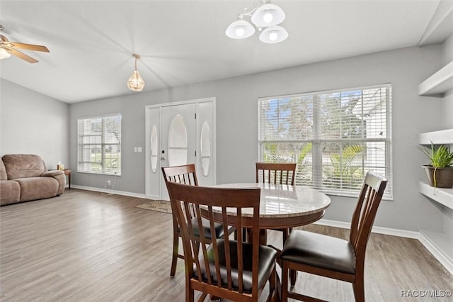 dining space with ceiling fan with notable chandelier and wood-type flooring