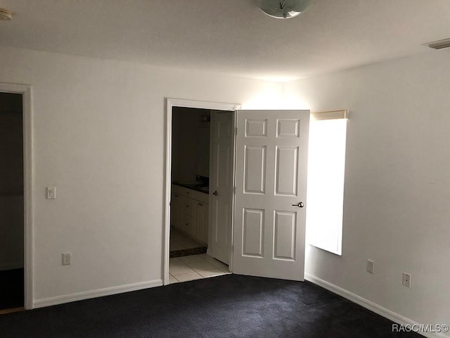 unfurnished bedroom featuring ensuite bathroom and light colored carpet