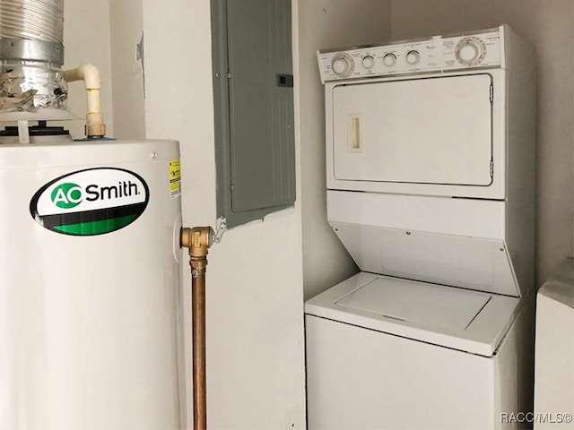 laundry area with stacked washer and clothes dryer, electric panel, and water heater