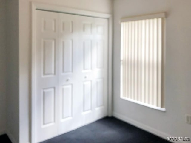 unfurnished bedroom with dark colored carpet and a closet