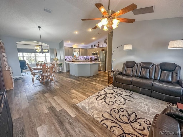 living room with hardwood / wood-style flooring, ceiling fan, and vaulted ceiling