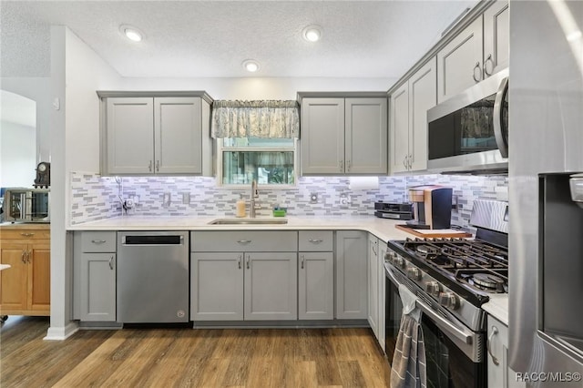 kitchen featuring gray cabinetry, sink, stainless steel appliances, and dark wood-type flooring