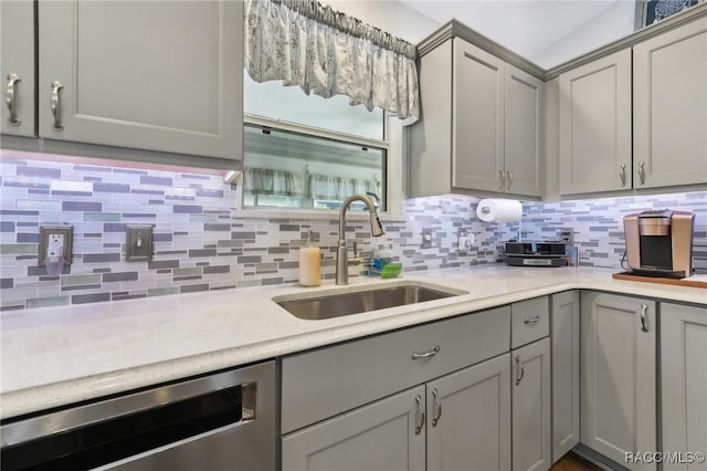 kitchen featuring stainless steel dishwasher, gray cabinetry, sink, and tasteful backsplash