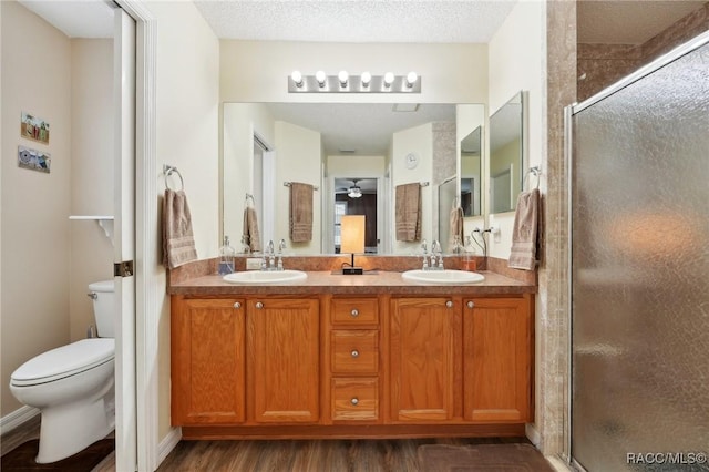 bathroom with wood-type flooring, a shower with shower door, a textured ceiling, and toilet