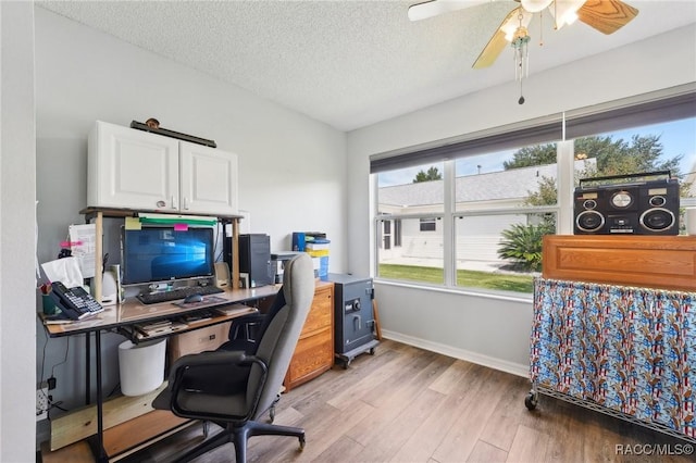 home office with ceiling fan, light hardwood / wood-style floors, and a textured ceiling