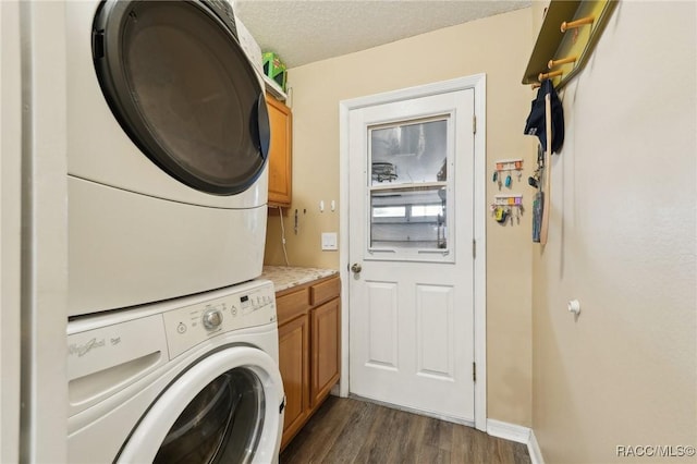 laundry room with stacked washer / drying machine, dark hardwood / wood-style floors, cabinets, and a textured ceiling