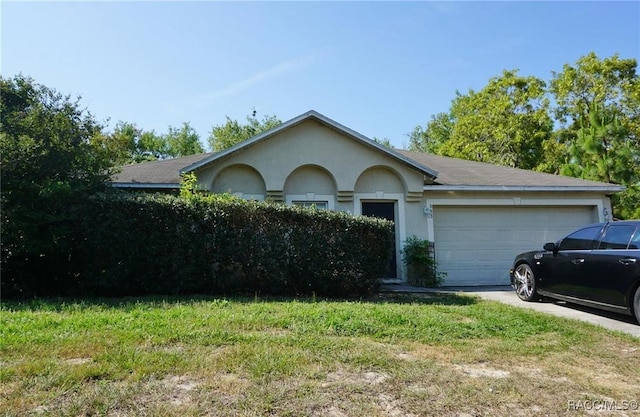 view of front of property with stucco siding, an attached garage, concrete driveway, and a front yard