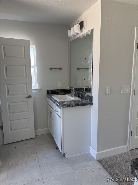 bathroom with vanity, baseboards, and a textured ceiling