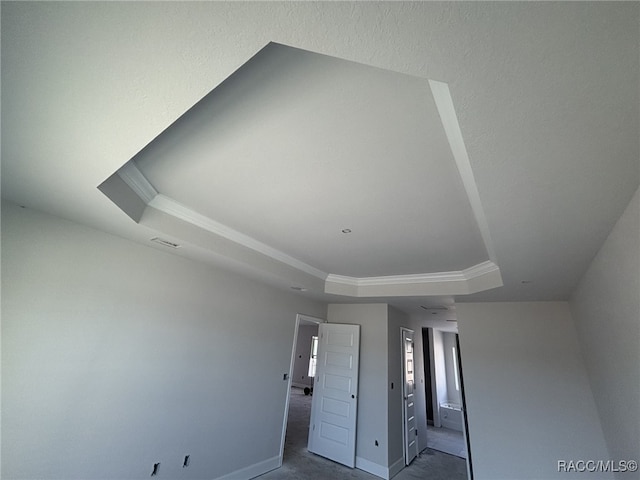 unfurnished bedroom with ornamental molding and a tray ceiling