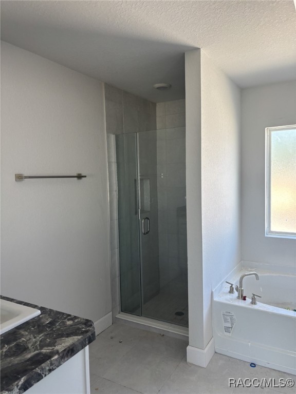 bathroom featuring baseboards, a garden tub, a textured ceiling, and a shower stall