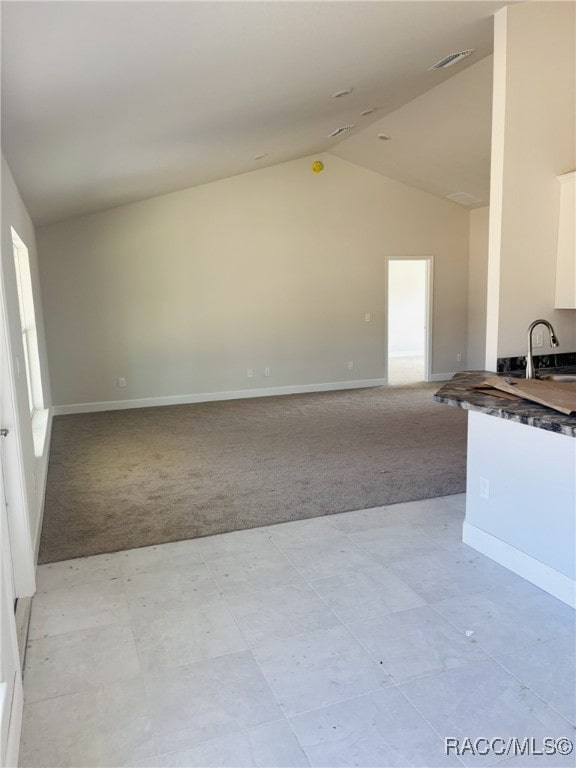 kitchen featuring open floor plan, white cabinets, a sink, and light carpet