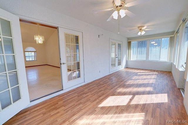 unfurnished sunroom with french doors and ceiling fan with notable chandelier