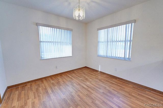 spare room with hardwood / wood-style flooring and a notable chandelier