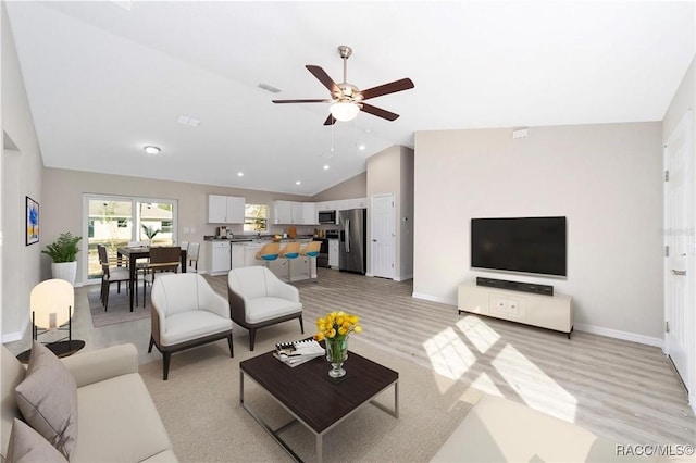 living room with light hardwood / wood-style floors, vaulted ceiling, and ceiling fan