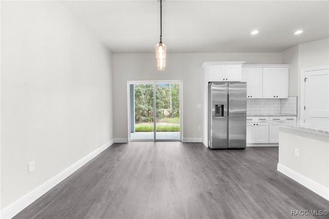 kitchen with white cabinetry, hanging light fixtures, stainless steel refrigerator with ice dispenser, light stone counters, and decorative backsplash