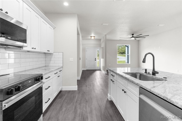 kitchen with appliances with stainless steel finishes, tasteful backsplash, sink, white cabinets, and light stone countertops