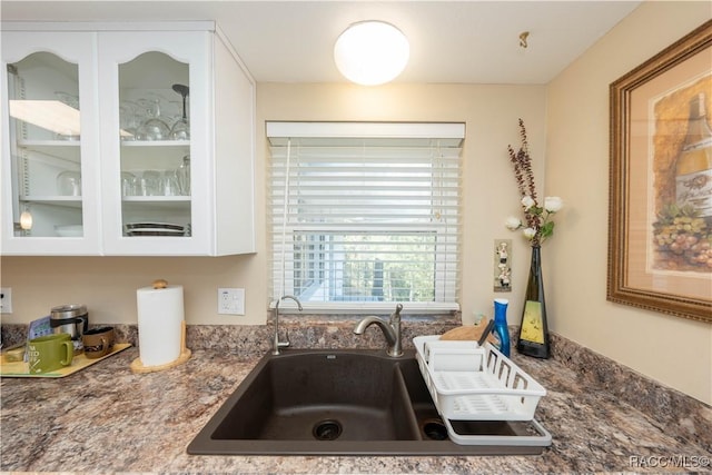 kitchen featuring white cabinetry, sink, and dark stone countertops