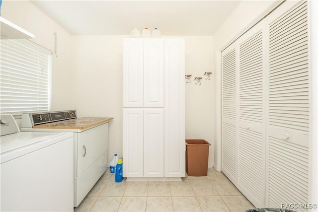 clothes washing area featuring light tile patterned floors, washer and clothes dryer, and cabinets