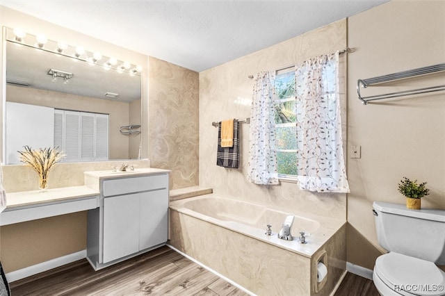 bathroom with hardwood / wood-style flooring, a washtub, toilet, and vanity