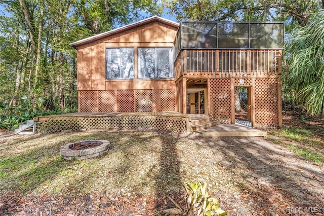 rear view of property with a sunroom, a deck, and an outdoor fire pit