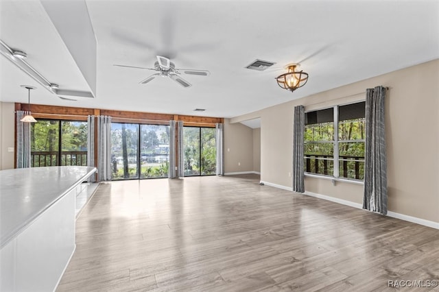 unfurnished living room featuring ceiling fan, light hardwood / wood-style floors, and a wealth of natural light