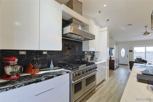 kitchen featuring dark stone countertops, double oven range, light hardwood / wood-style flooring, and white cabinets