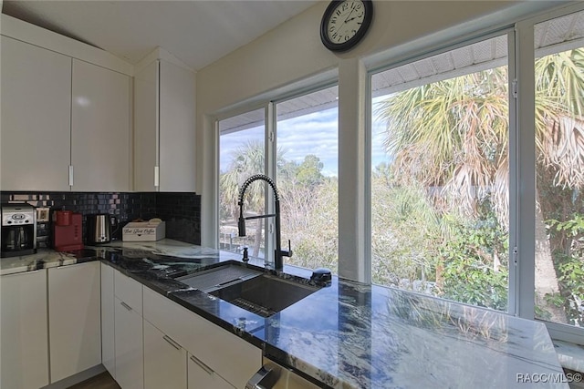 kitchen featuring white cabinets, sink, decorative backsplash, and dark stone countertops