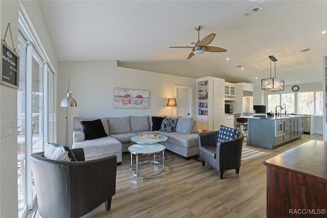 living room with ceiling fan, sink, light hardwood / wood-style floors, and vaulted ceiling