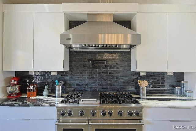 kitchen featuring white cabinetry, wall chimney range hood, and double oven range