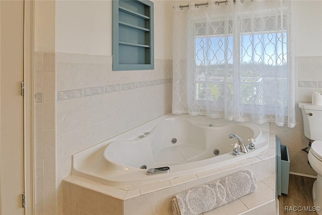 bathroom with tiled tub, tile walls, and toilet