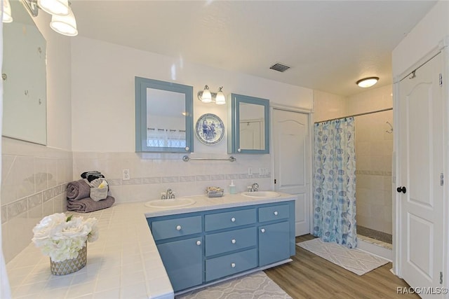 bathroom featuring wood-type flooring, curtained shower, vanity, and tile walls