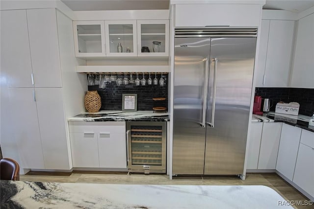 kitchen with white cabinetry, light wood-type flooring, beverage cooler, and built in refrigerator