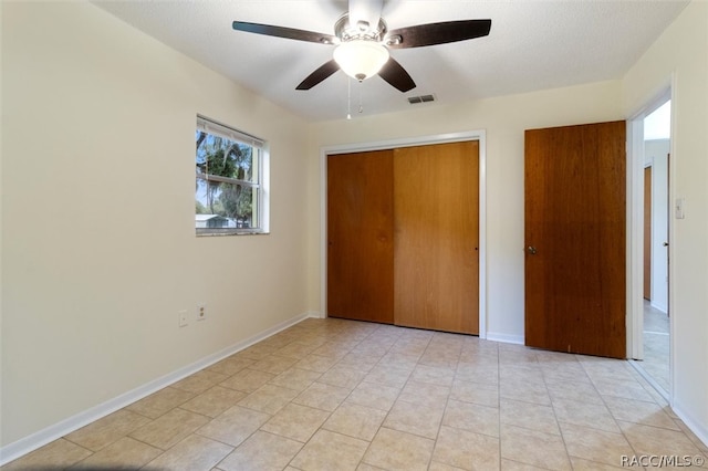 unfurnished bedroom with light tile patterned floors, a textured ceiling, a closet, and ceiling fan