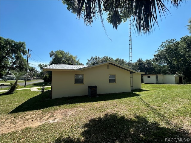 view of property exterior featuring a lawn, a storage unit, and central air condition unit