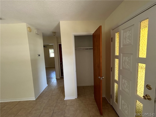 hall featuring light tile patterned floors and a textured ceiling