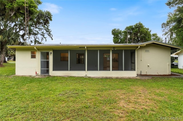 back of house featuring a lawn and a sunroom