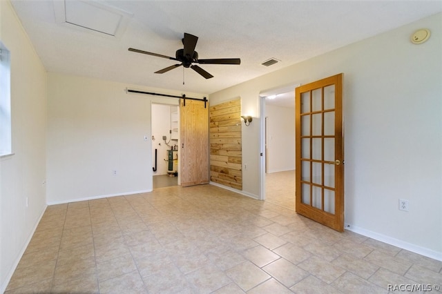 unfurnished room with a barn door and ceiling fan