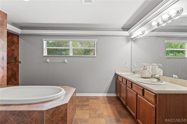 full bath with a relaxing tiled tub, a sink, baseboards, and double vanity