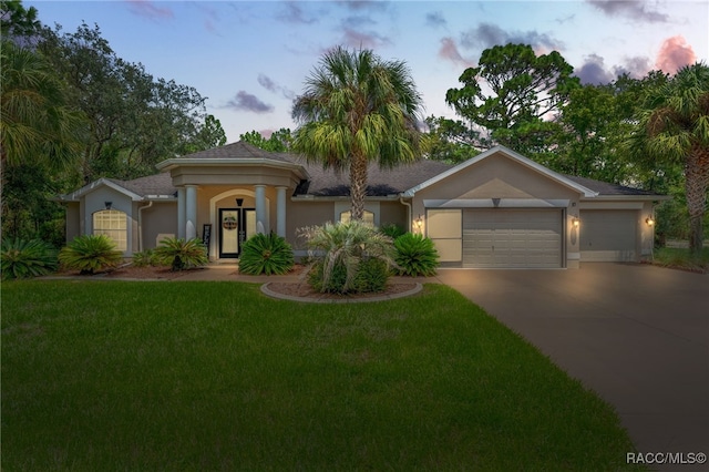 view of front of home with concrete driveway, a lawn, an attached garage, and stucco siding